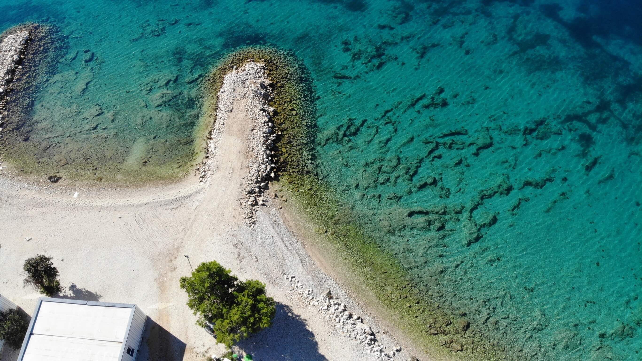 Detailní záběr na pláž a tyrkysové moře, foceno z dronu