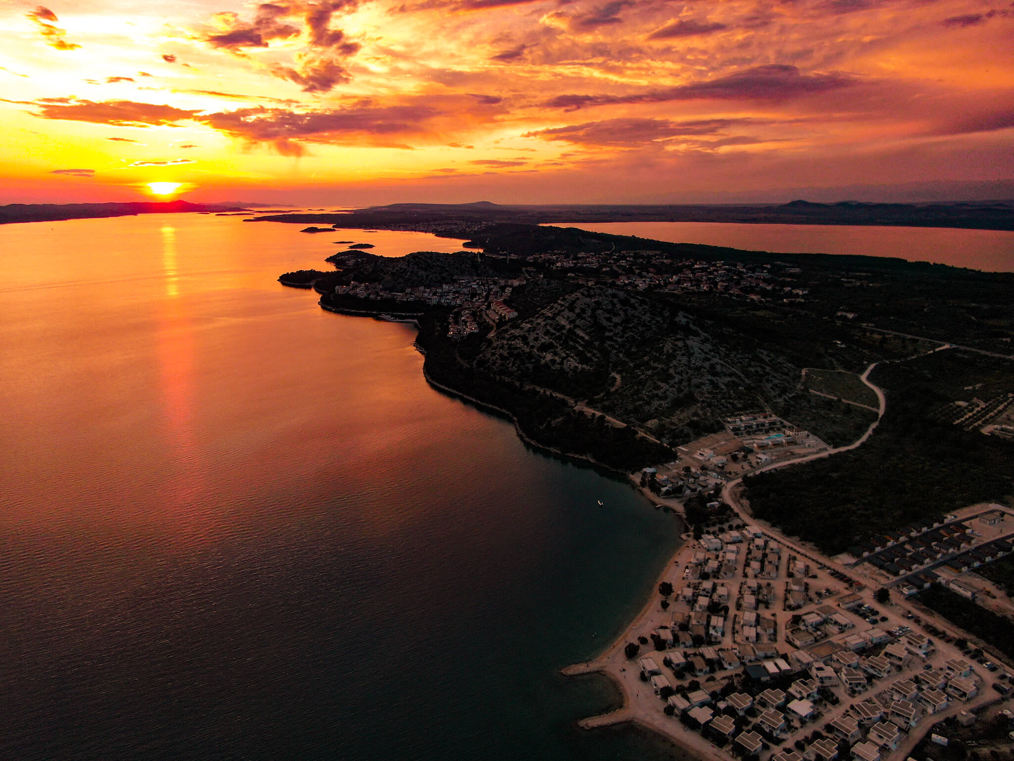 Resort s pláží a všemi ostatními vily při západu slunce, foceno z dronu